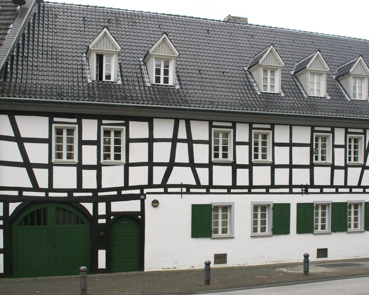 Fachwerkhaus mit grünem Hoftor und grünen Fensterläden an der Hauptstraße im Ortskern von Niederdollendorf