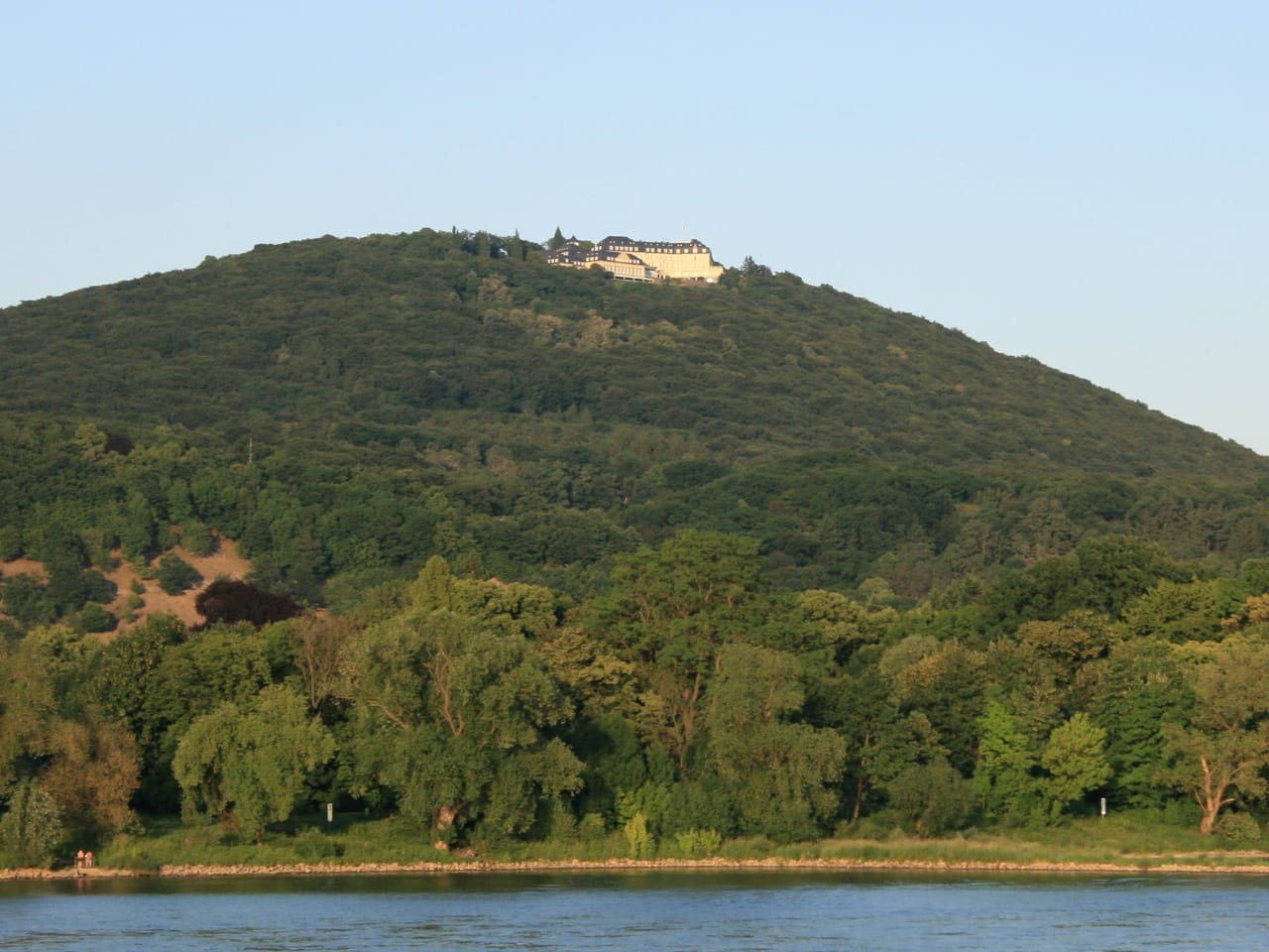 Der bewaldete Petersberg über dem Rhein, auf dem Gipfel das Gästehaus der Bundesregierung